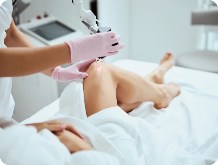 Praticienne réalisant un soin esthétique au laser sur le genou d'une cliente